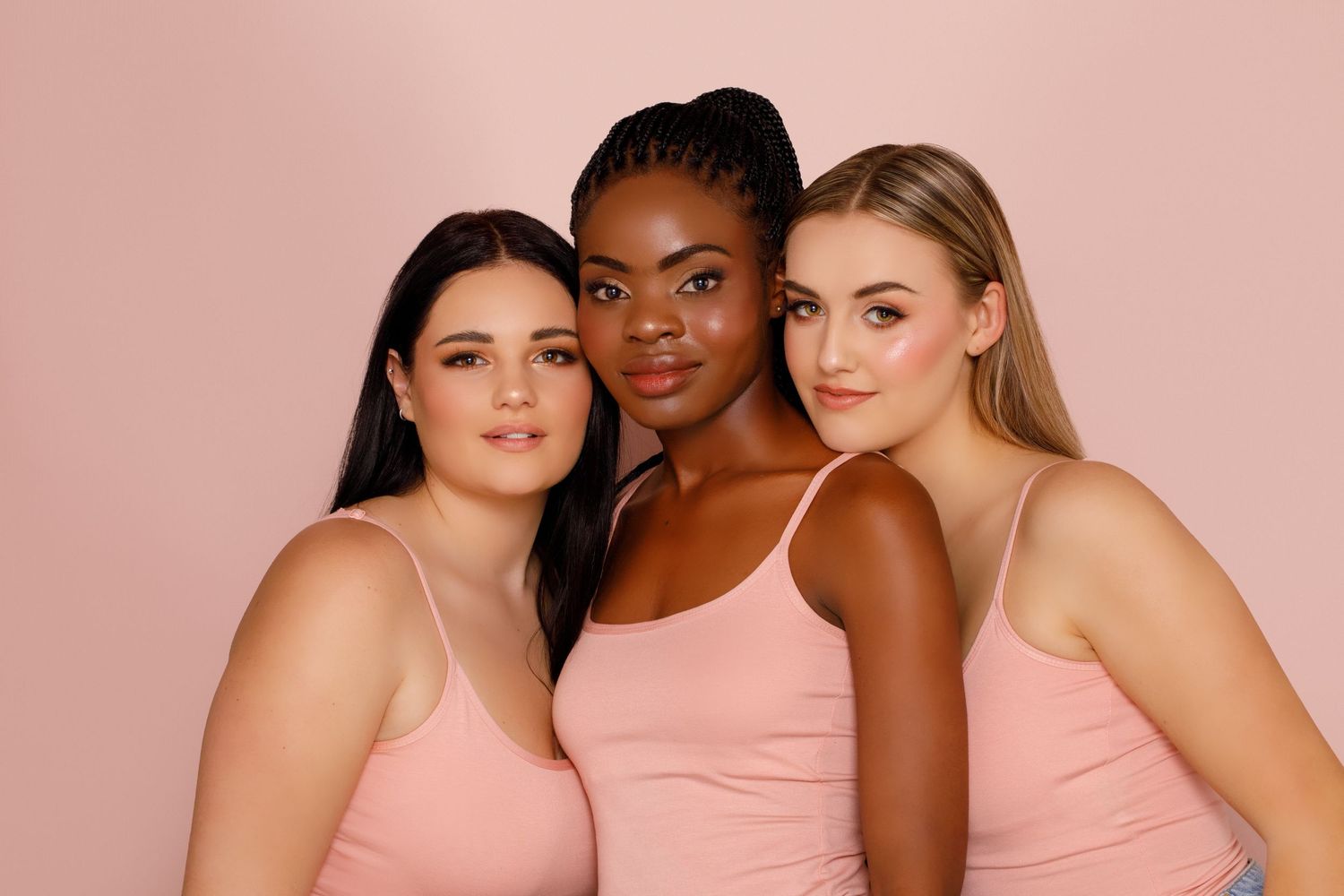 A group of diverse models pose together wearing matching pink outfits against a soft pink background.
