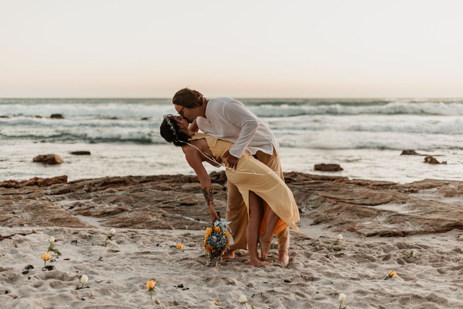 Two beach engagement photos shot at sunset on rocky coastline with ocean waves in the background.
