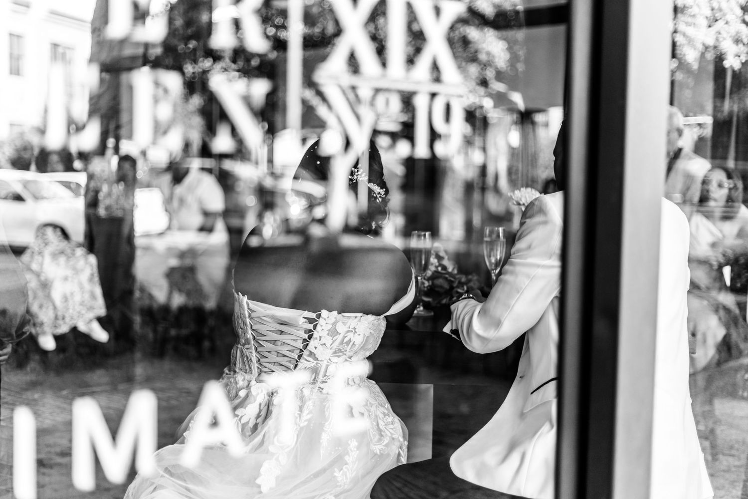 Black and white reflection in storefront window shows a vintage corset dress display with text lettering overlay.