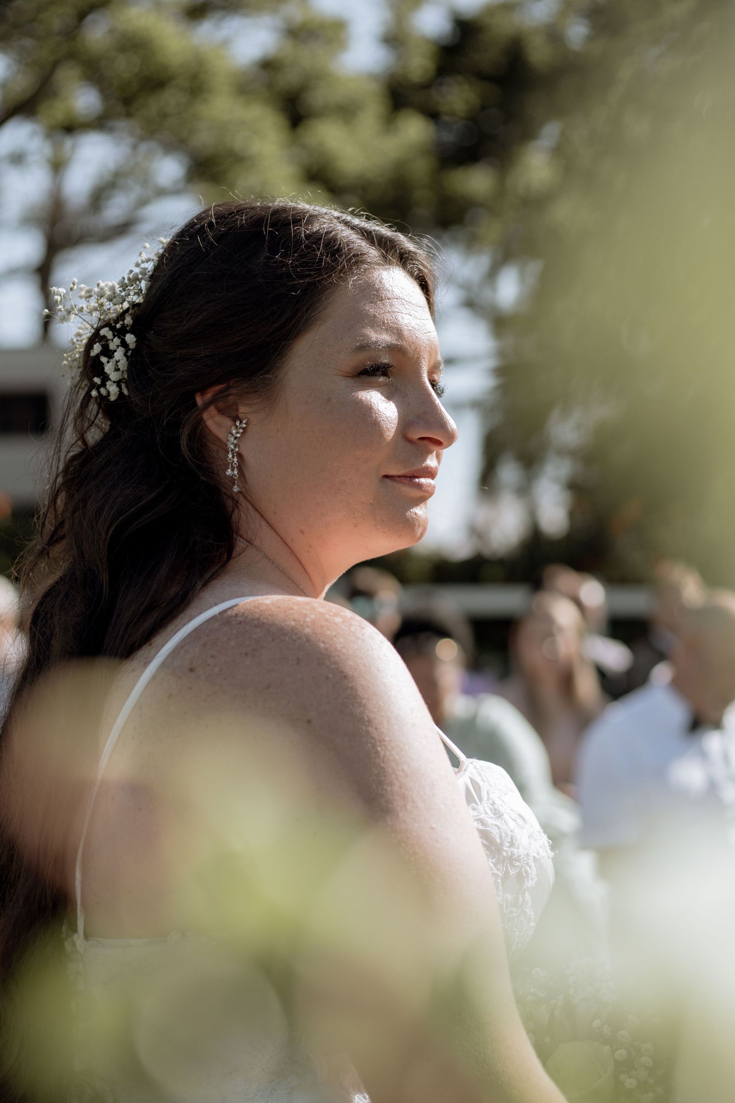 A bride in white glances to the side while captured in a romantic outdoor photo sequence.