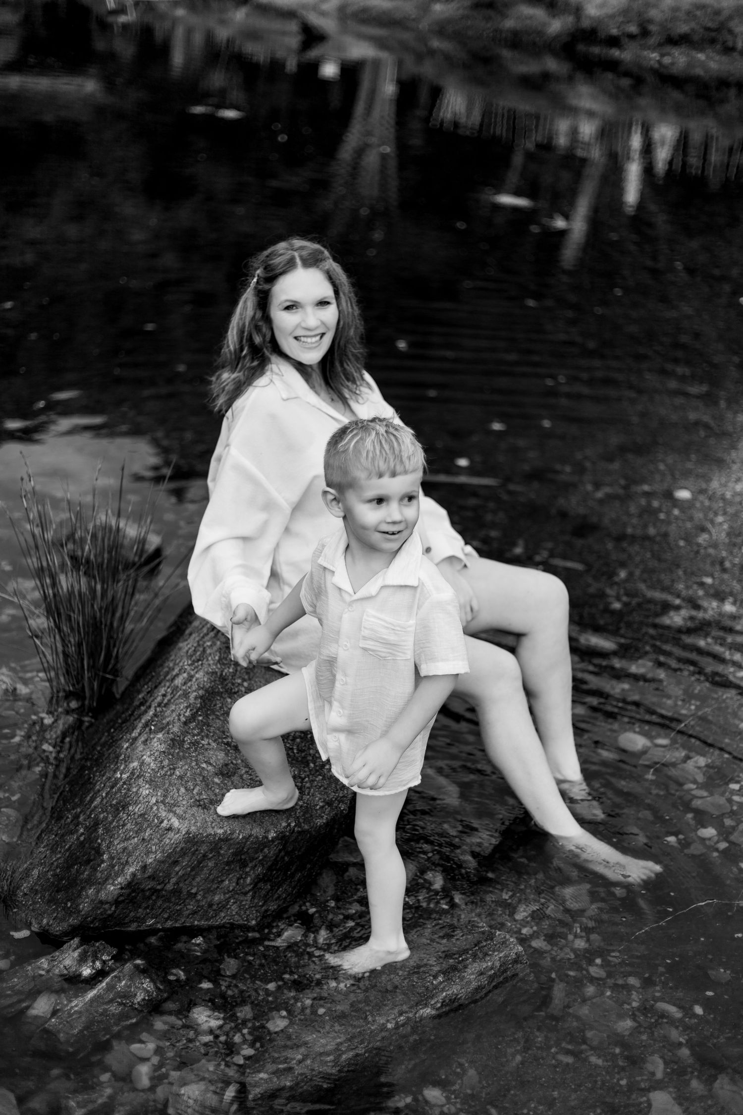 Three black and white photos show playful outdoor exploration at a muddy creek bank while wearing white clothing.