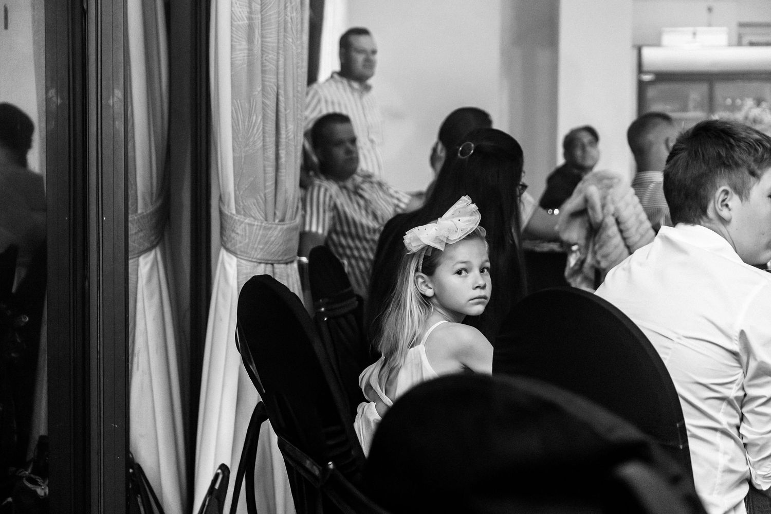 Black and white image showing people dancing and mingling at a social gathering.