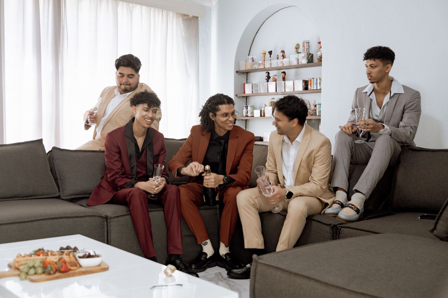 People sitting on a gray couch in a bright modern living room having animated conversation.