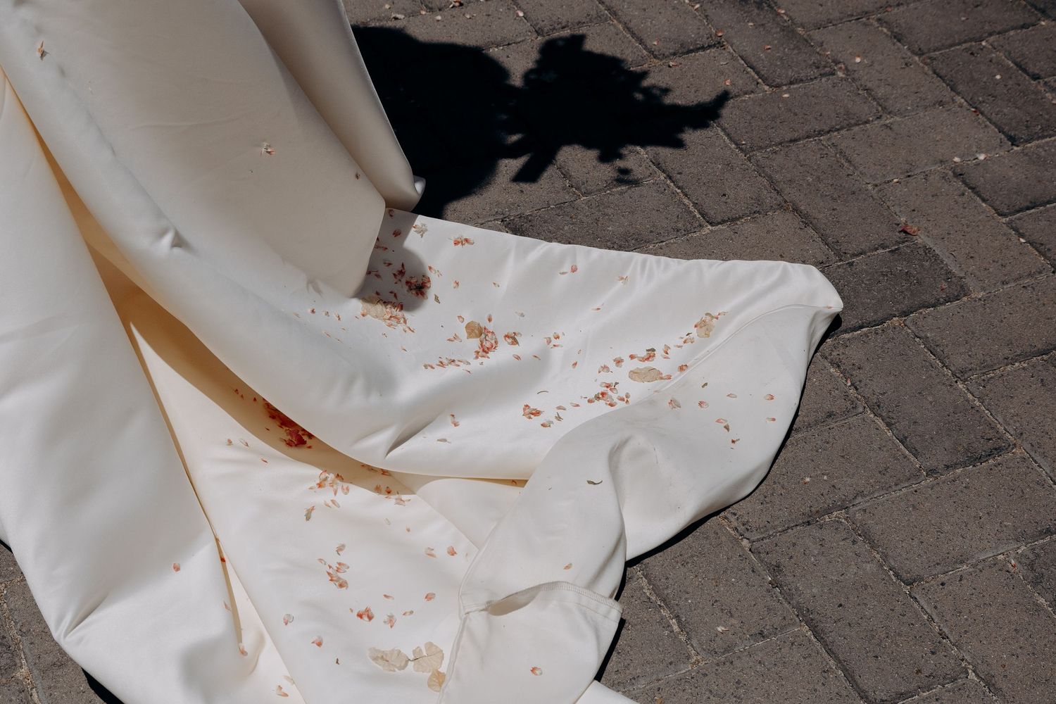 White paper towels with red stains are scattered across a dark brick paved surface.