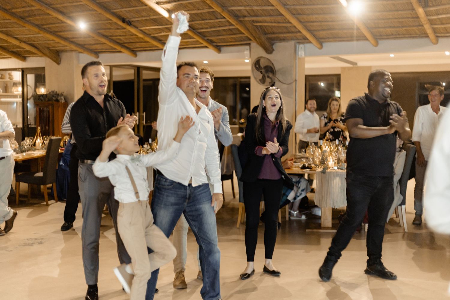 People dancing together in a well-lit indoor venue with hardwood floors and a festive atmosphere.