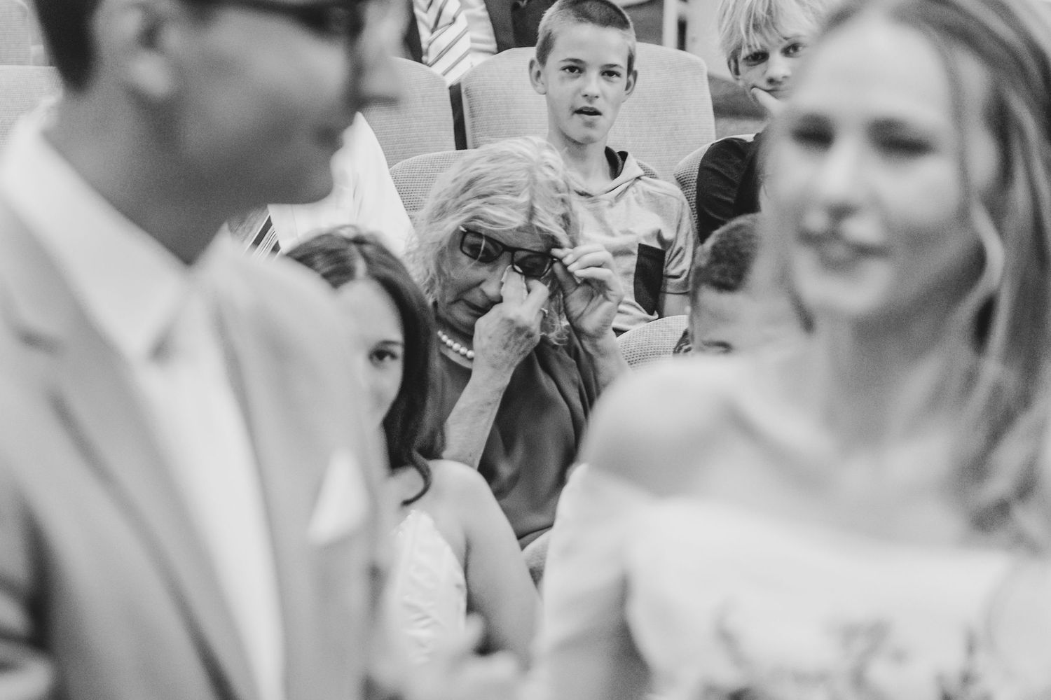 A group of wedding guests share joyful laughter during an outdoor celebration.