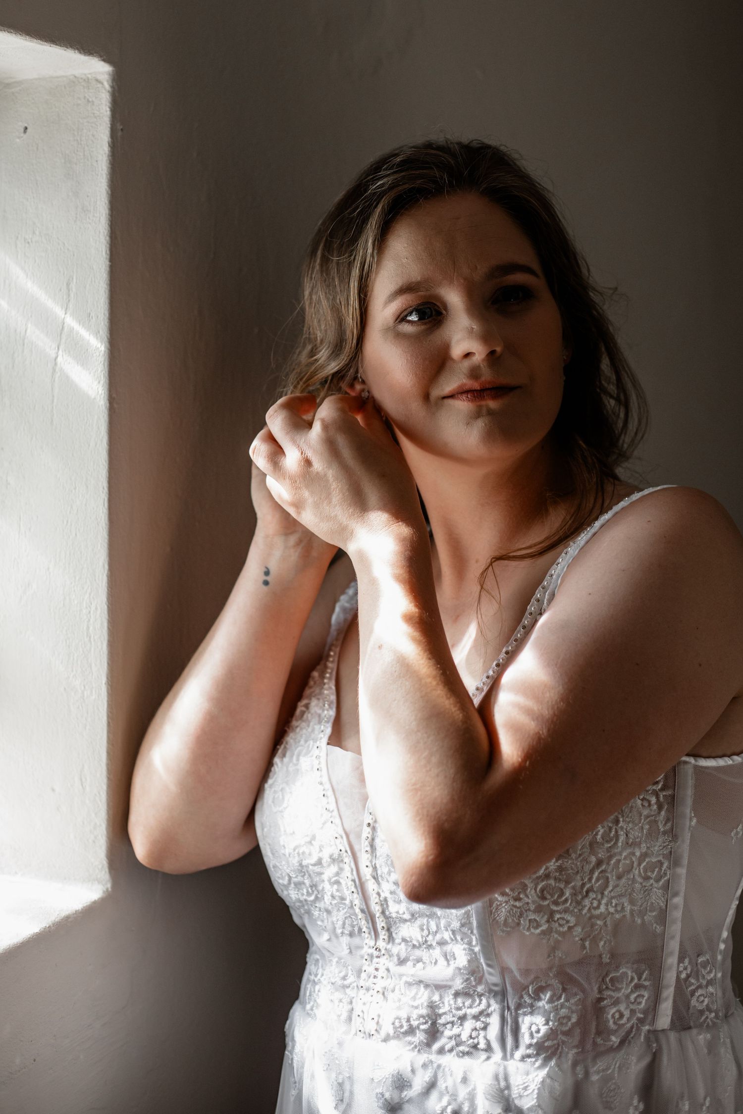 A sequence of artistic portraits in low light shows a person in a white lace dress against a dark background.