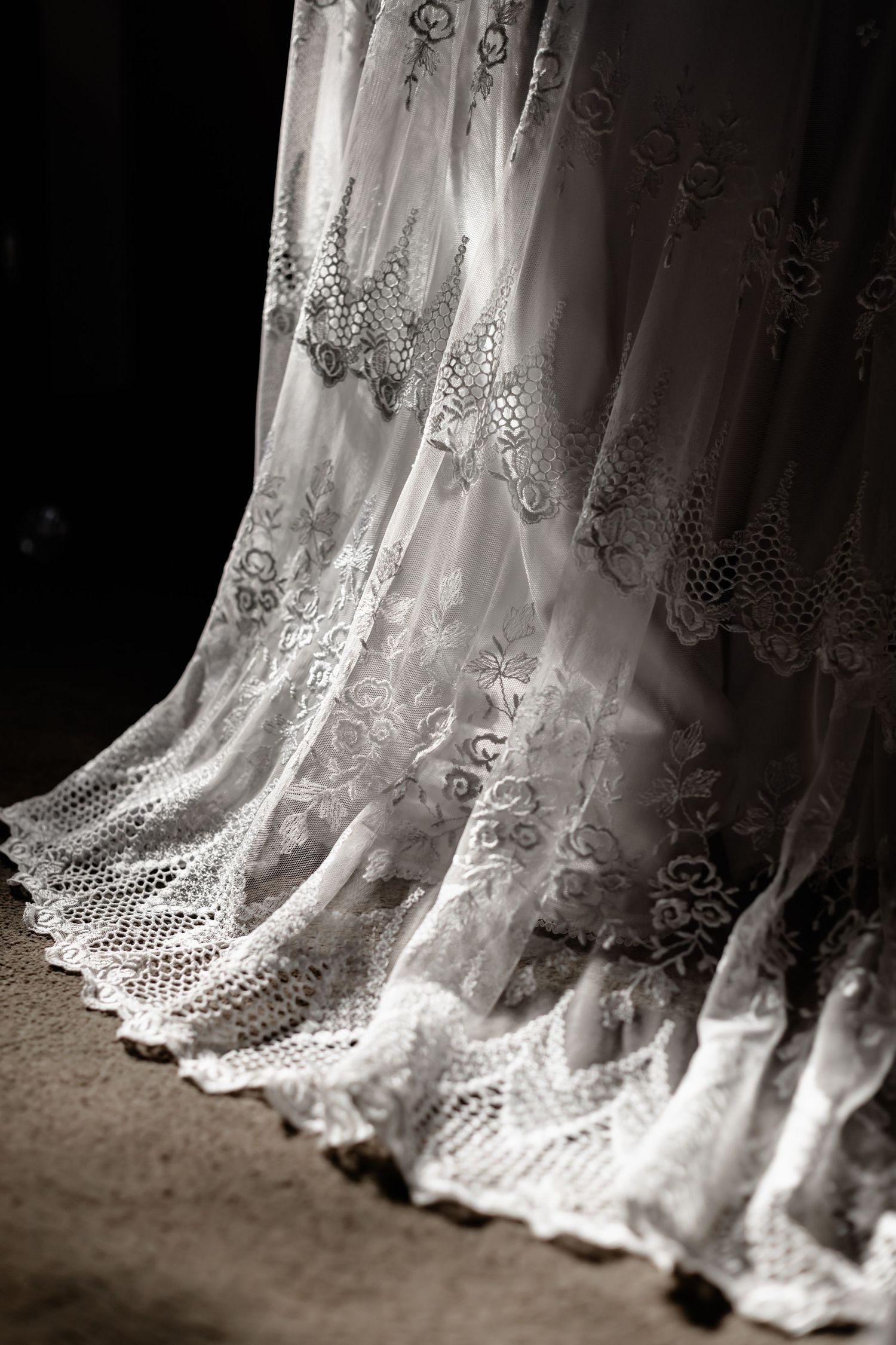 Delicate white lace curtains with an intricate floral pattern create an elegant cascading effect in a romantic setting.