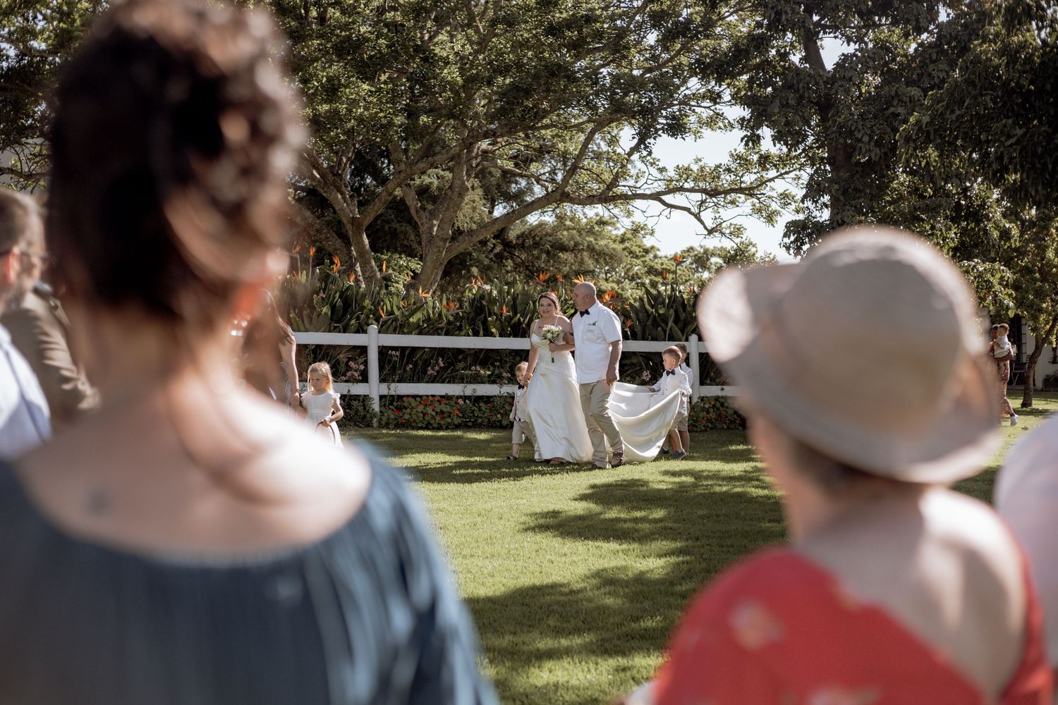 A collection of candid outdoor wedding ceremony shots showing guests on a sunny day with trees in the background.