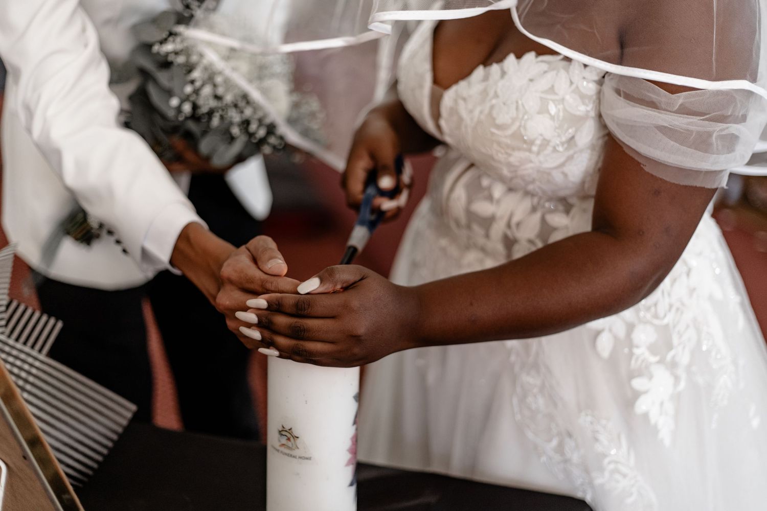 Hands exchanging wedding rings during a wedding ceremony, with the bride wearing a white lace dress.