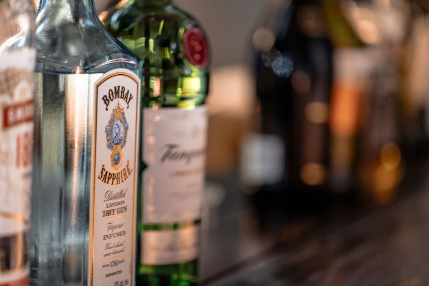 Blurred liquor bottles line a dimly lit bar shelf with warm ambient lighting creating a cozy atmosphere.