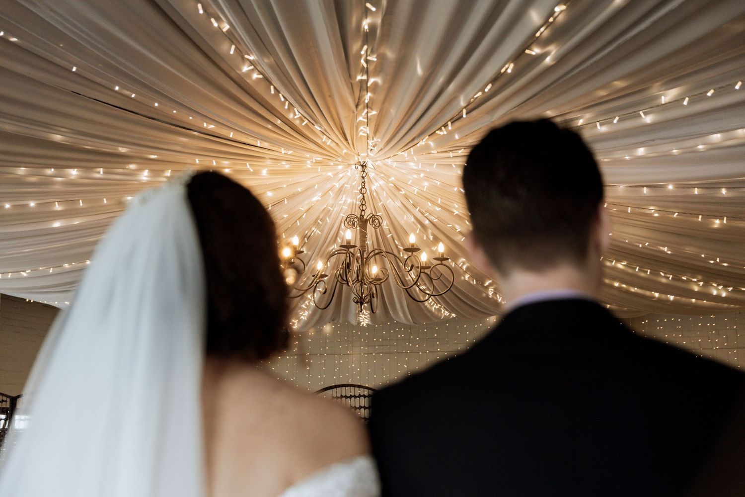 A series of six wedding photos showing couples dancing under elegant crystal chandeliers at an elegant reception venue.