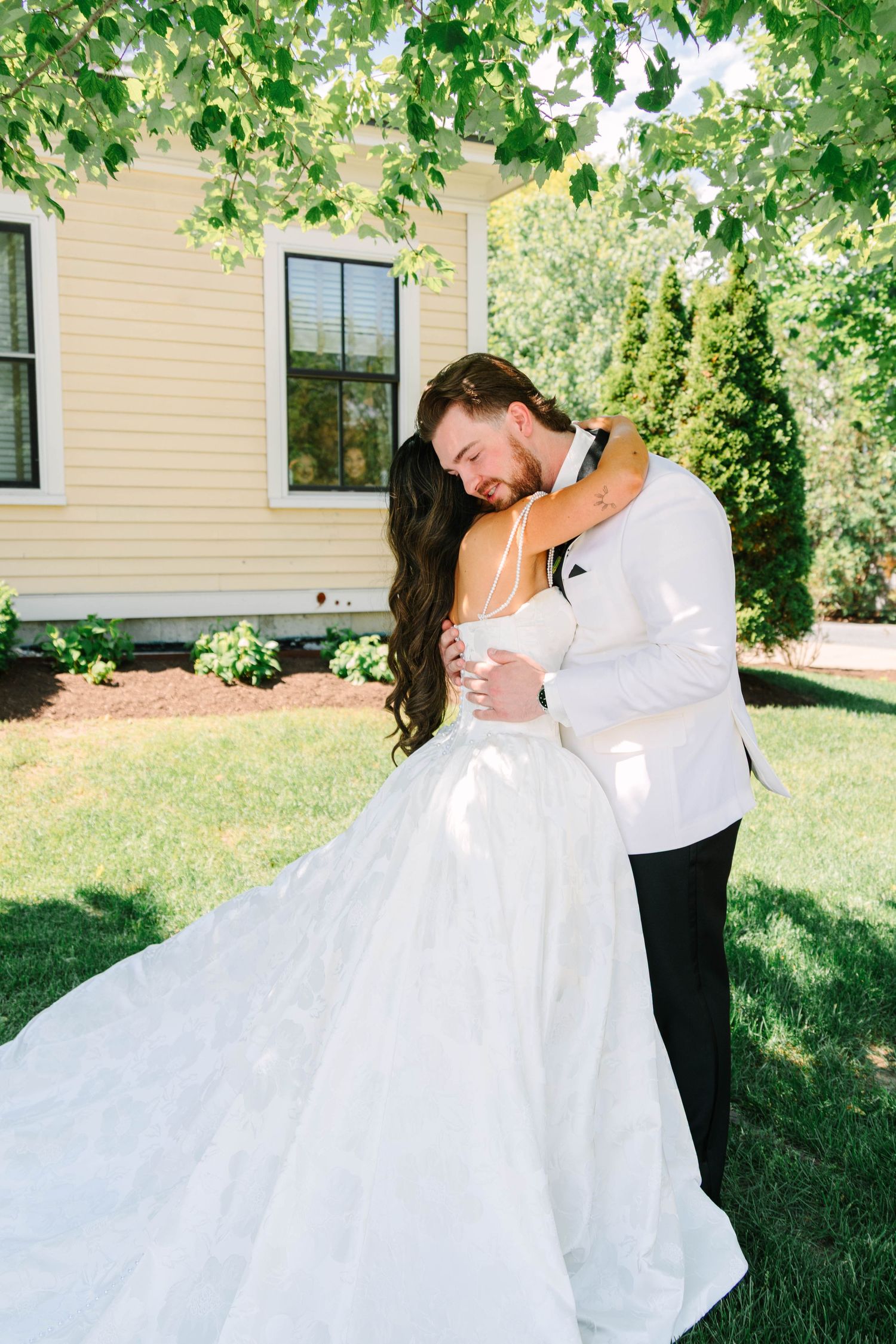 Bride and groom sharing tender embrace in garden after first look at outdoor summer wedding.