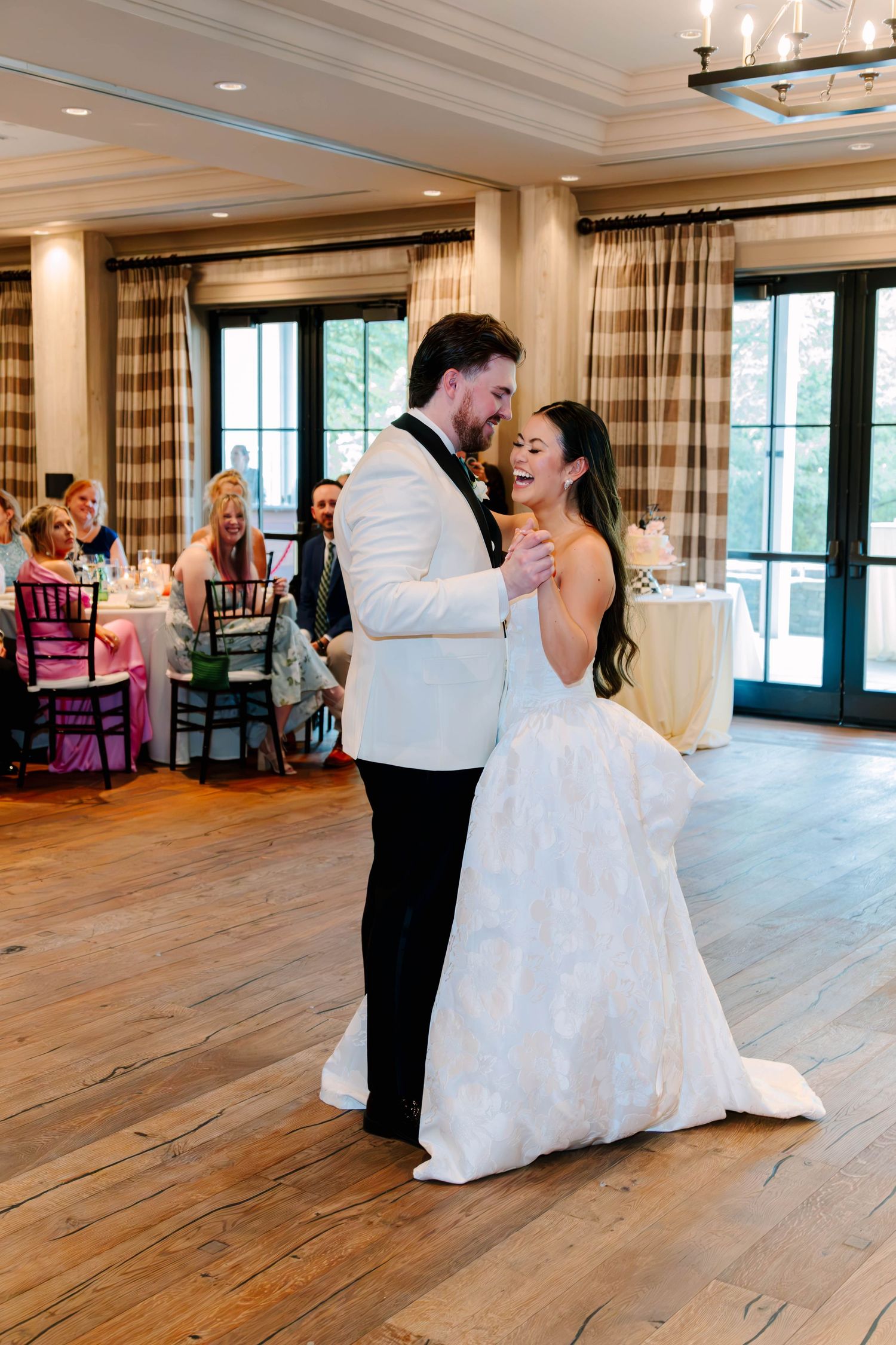 Bride and groom share romantic first dance on wooden floor at elegant wedding reception.