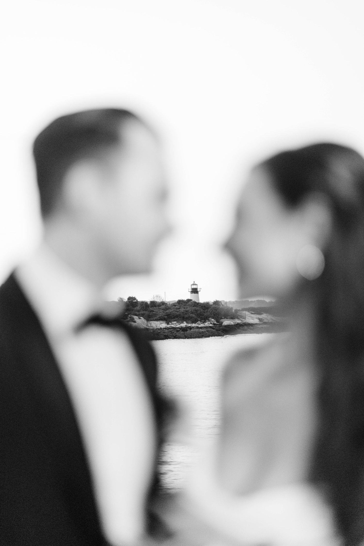 Black and white double exposure photo of bride and groom with a lighthouse island in the background.