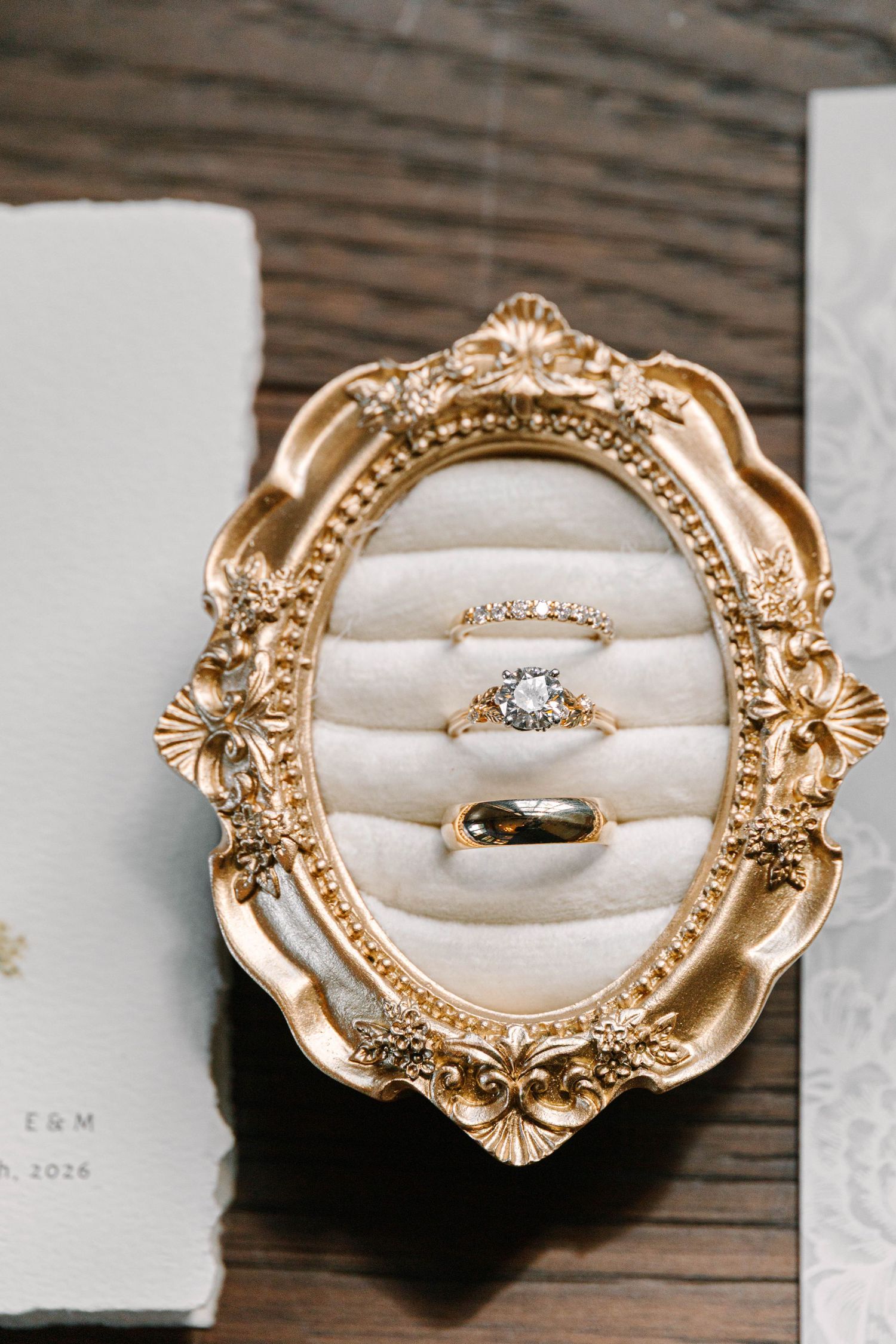 Three elegant gold wedding rings displayed in an ornate vintage gold oval ring dish.