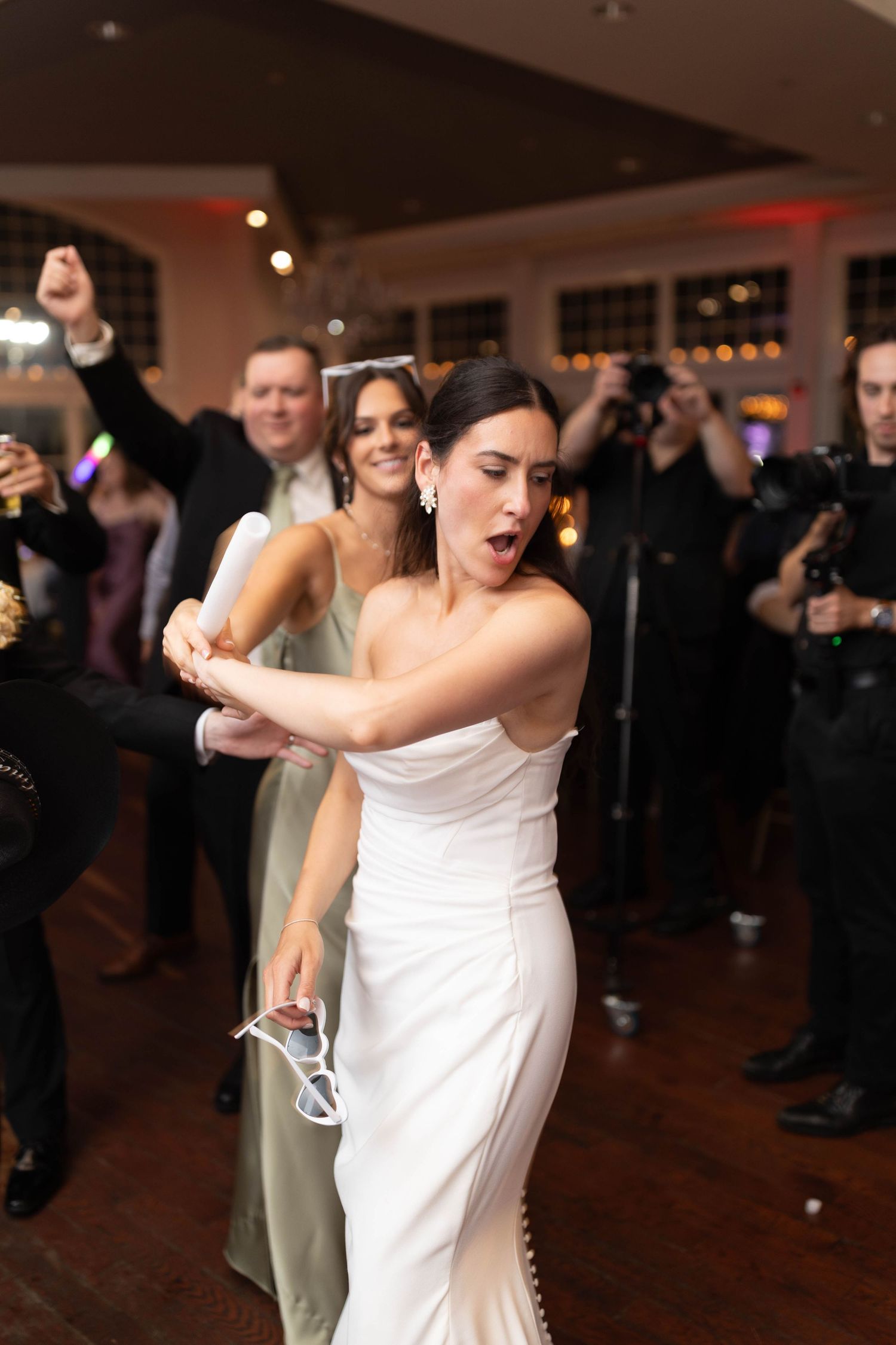 Bride in white strapless gown dancing energetically at wedding reception.