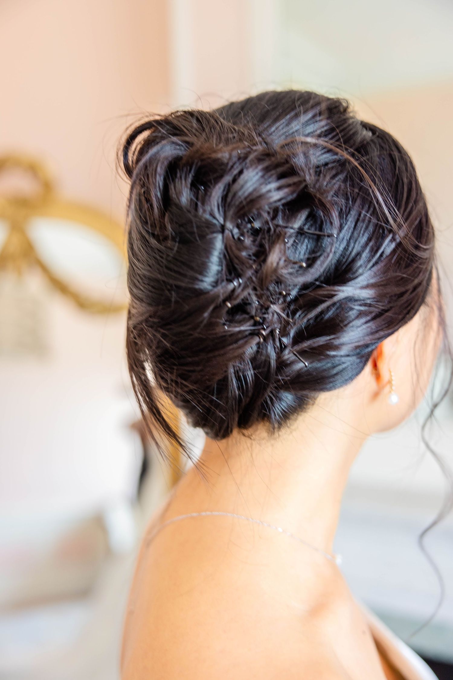 Back view of bride's dark hair styled in an elegant twisted updo with delicate crystal pins.