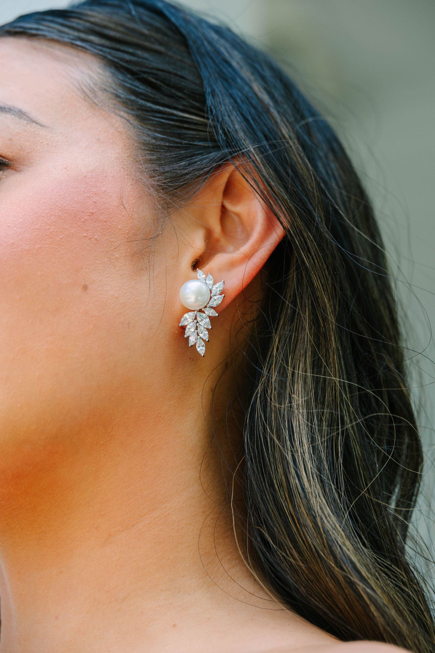 Bride wearing elegant pearl and crystal leaf-shaped earring on her wedding day.