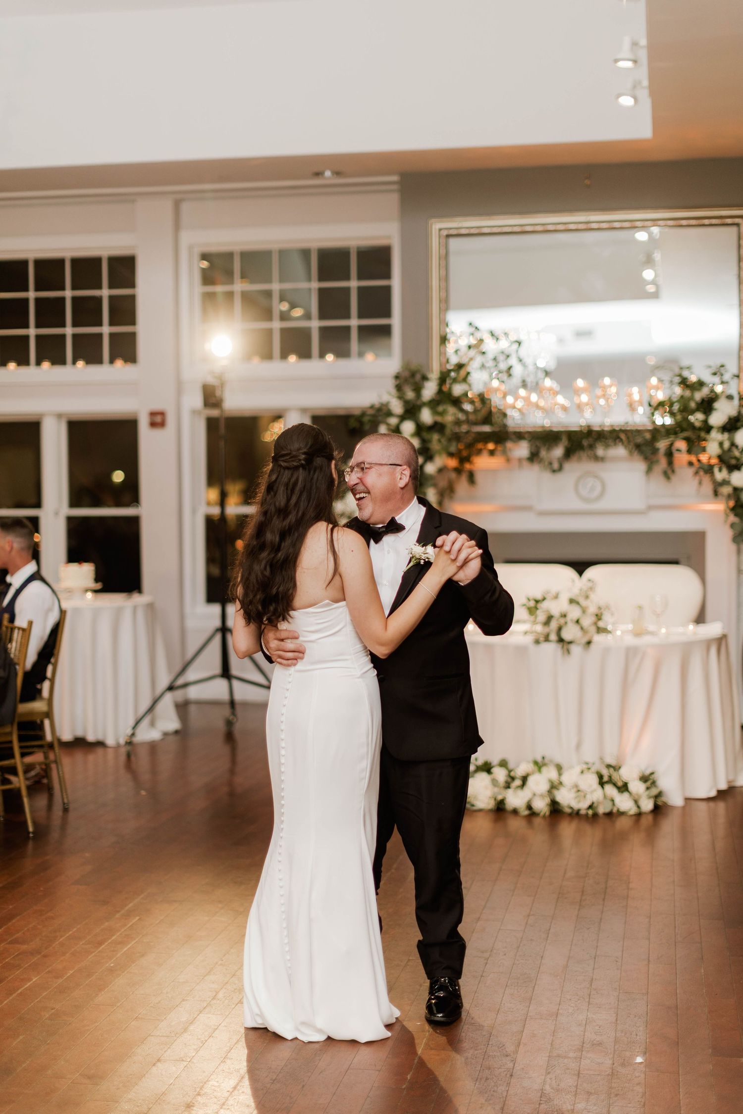 Bride and father share joyful father-daughter dance at elegant wedding reception venue.