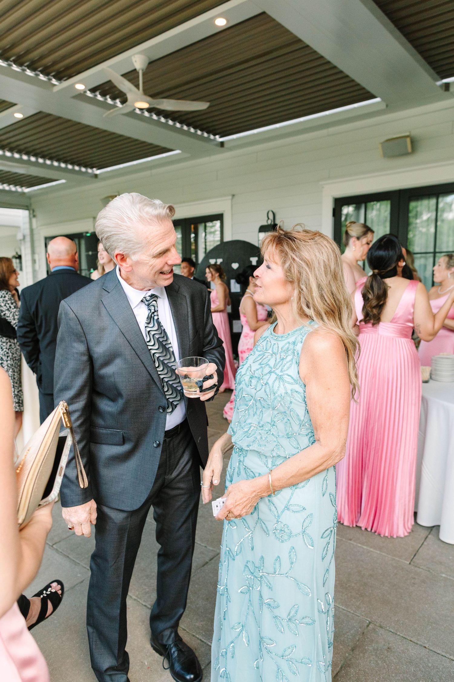 Elegantly dressed older couple shares a conversation at a wedding reception venue.