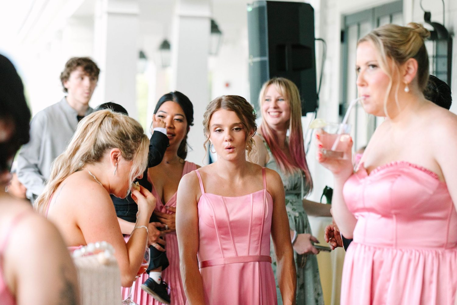 Bridesmaids in pink dresses gather around a bride during wedding reception celebrations.