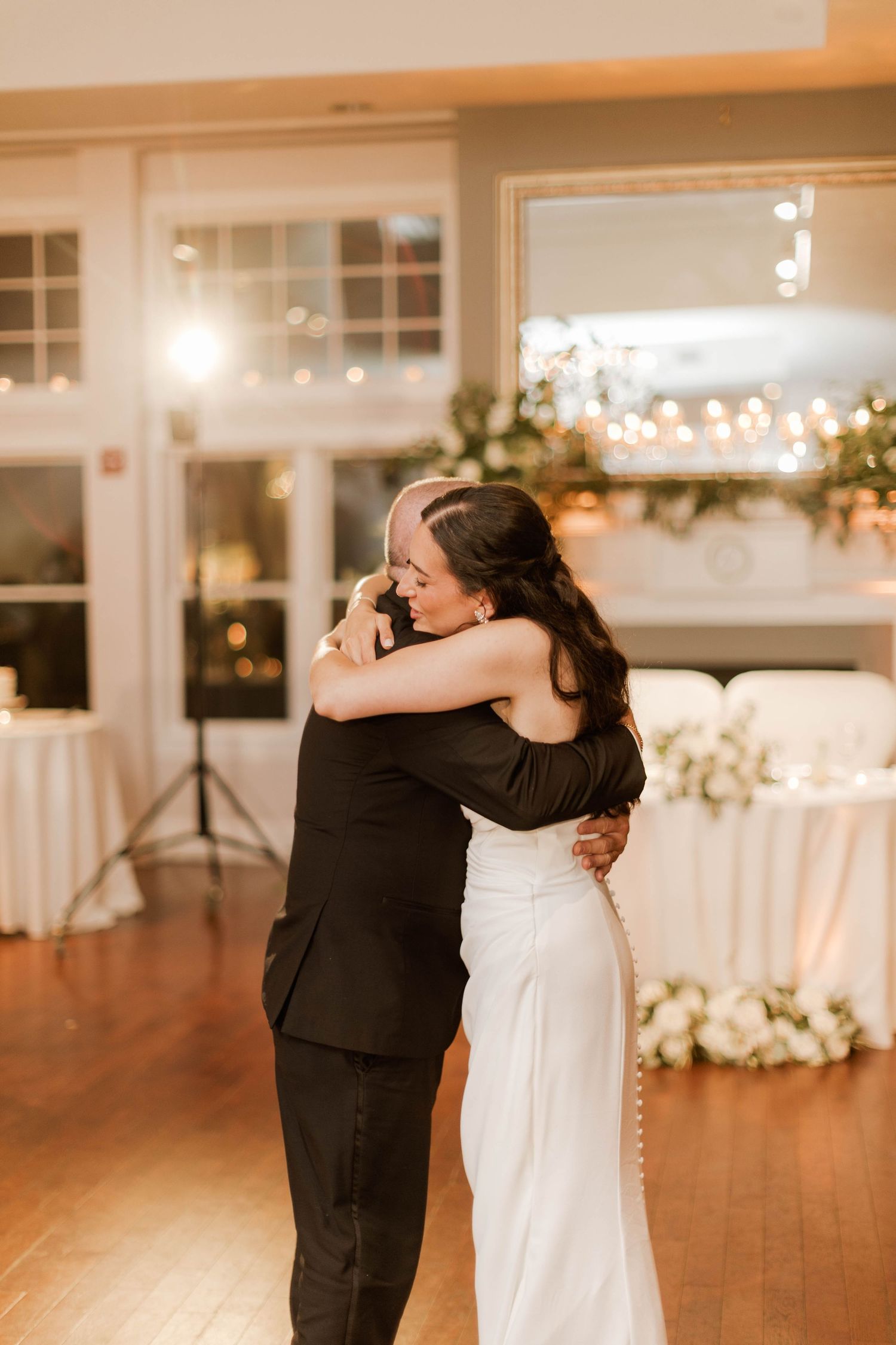 Bride and groom share an emotional embrace during their first dance at a romantic wedding reception.