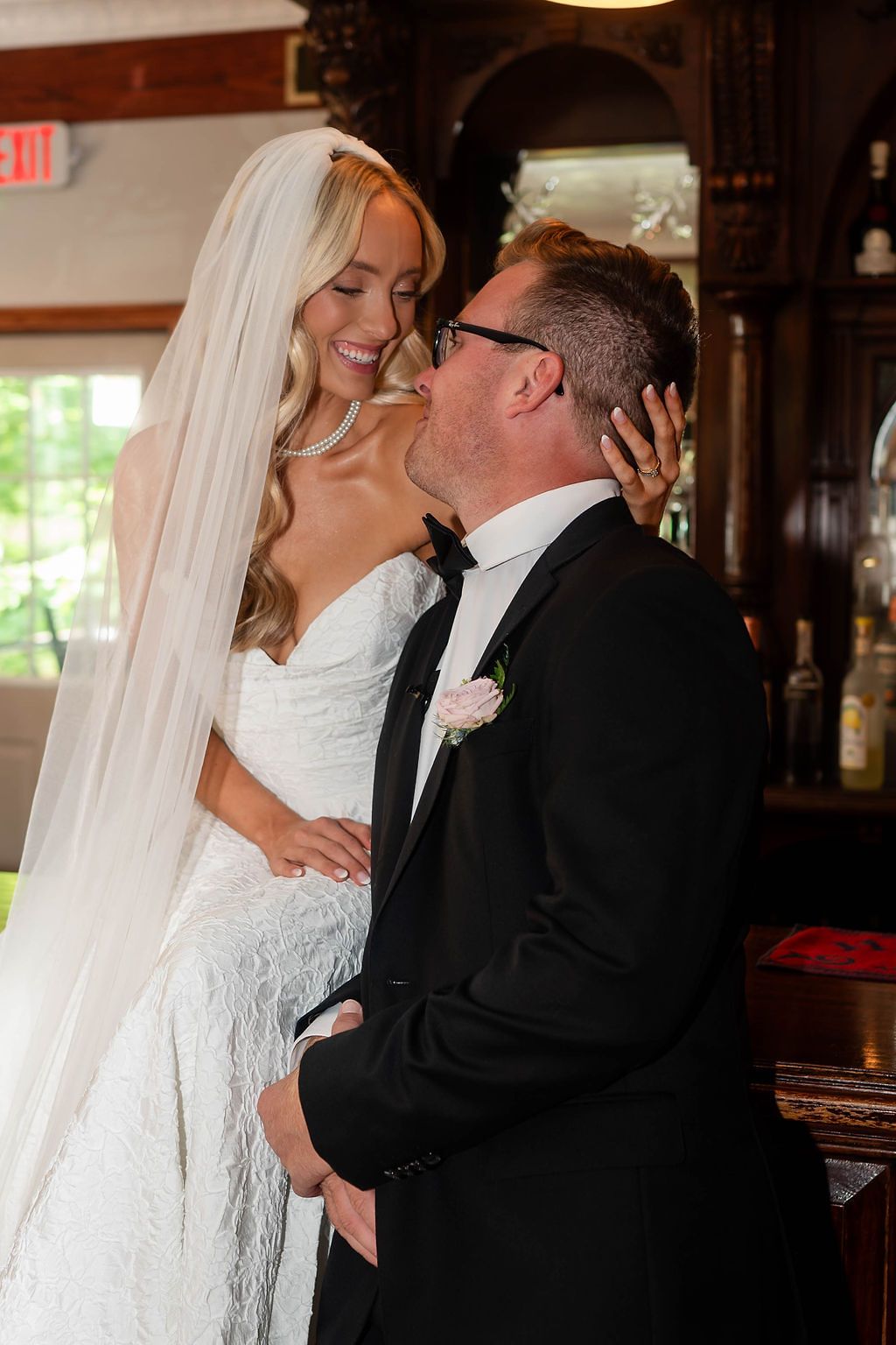 Bride and groom sharing a tender kiss inside a warmly lit venue.