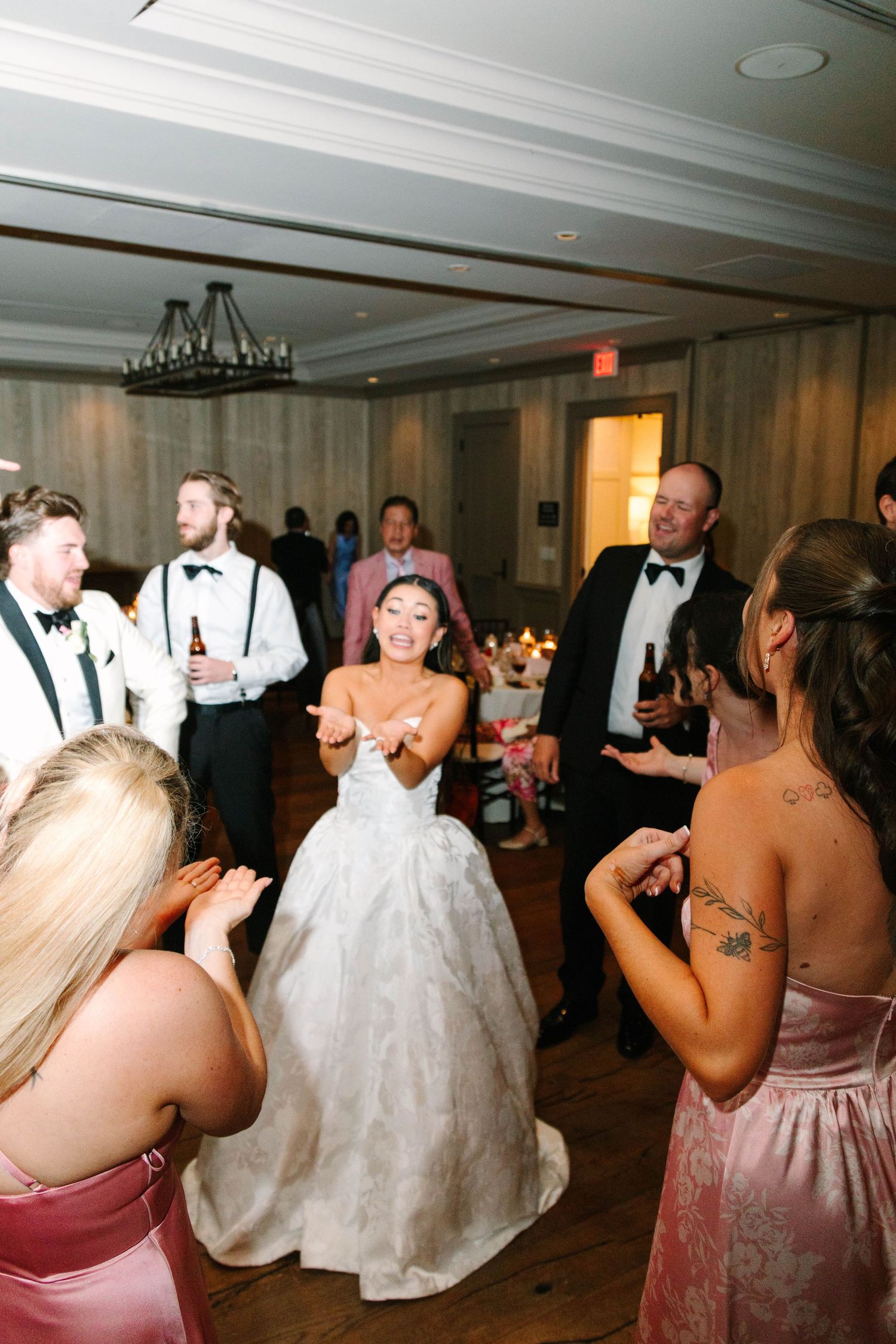 Bride in white ballgown dancing and celebrating joyfully with guests at wedding reception.
