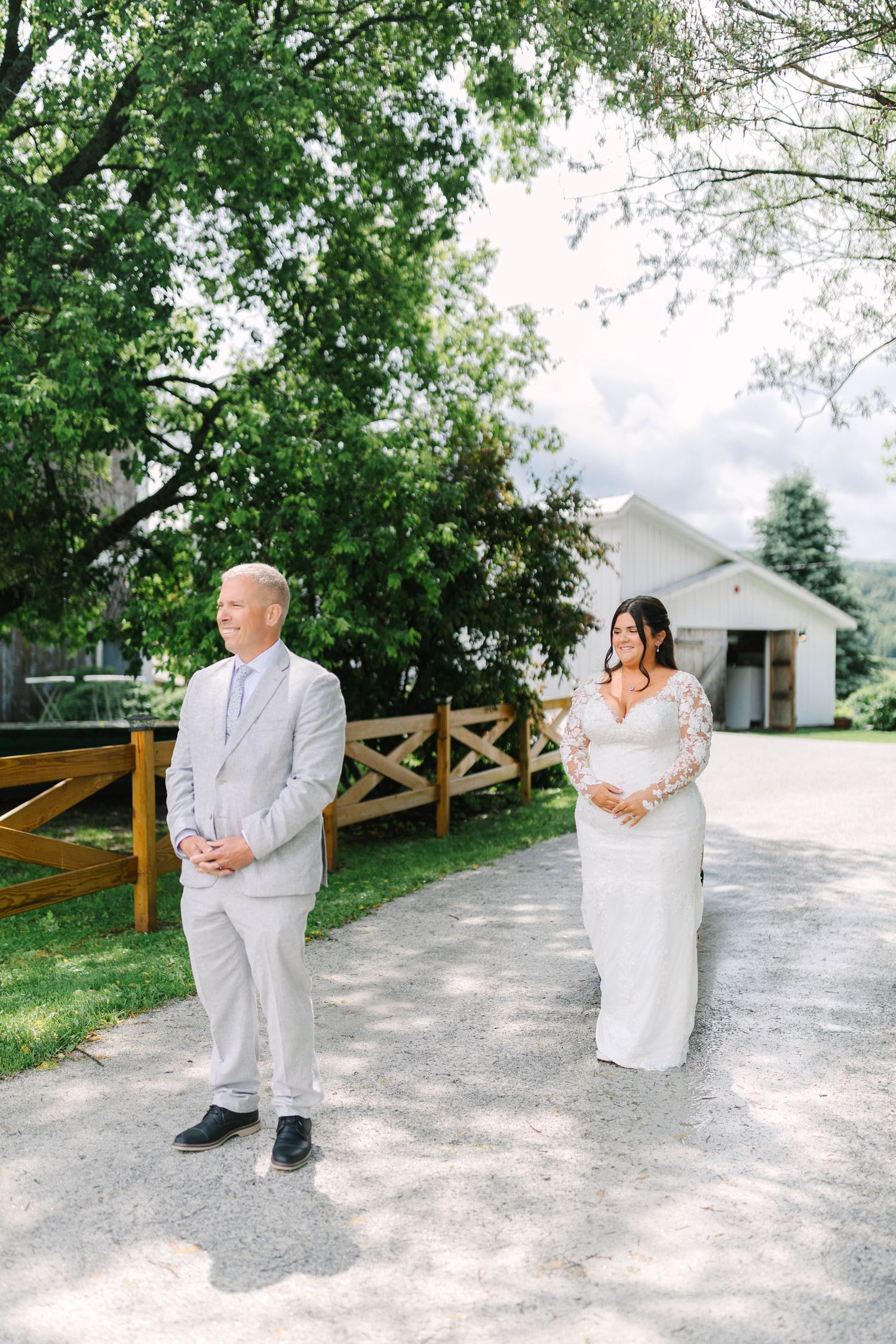 Bride approaches groom from behind during an emotional outdoor wedding first look on a sunny day.