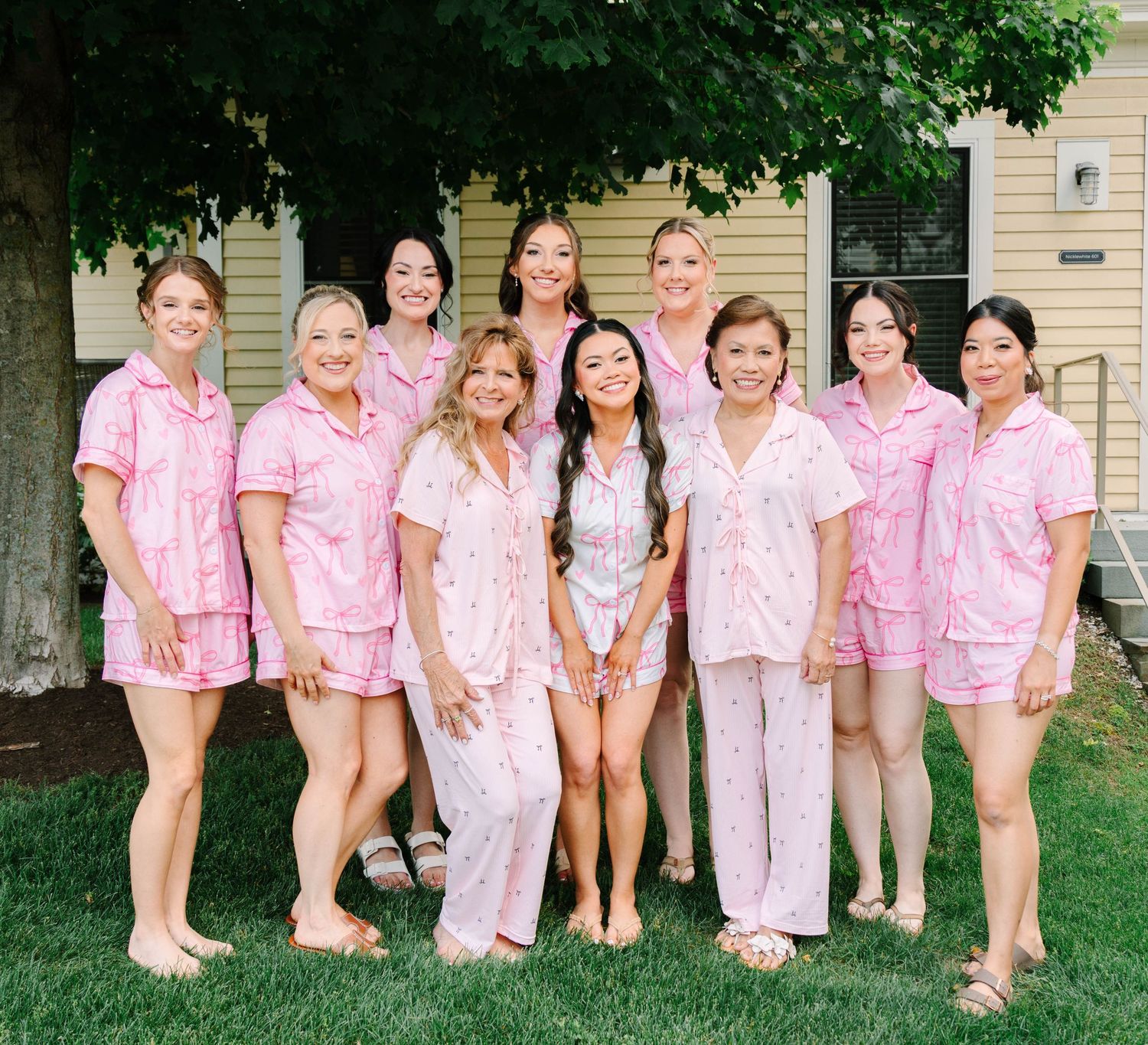 Bride and bridesmaids posing in matching pink pajamas outdoors.