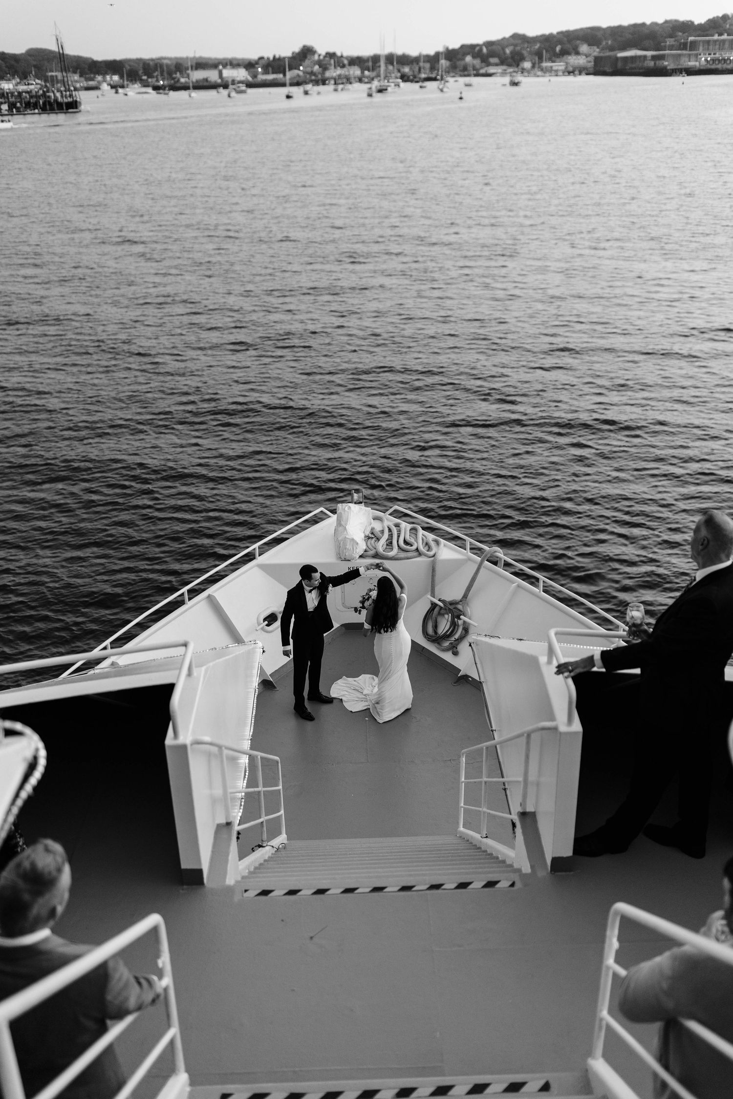 Aerial view of bride and groom exchanging vows on the bow of a yacht surrounded by open water.