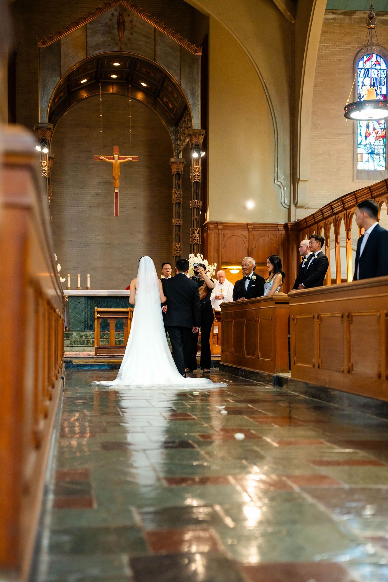 Bride in white gown and veil stands at church altar during wedding ceremony.