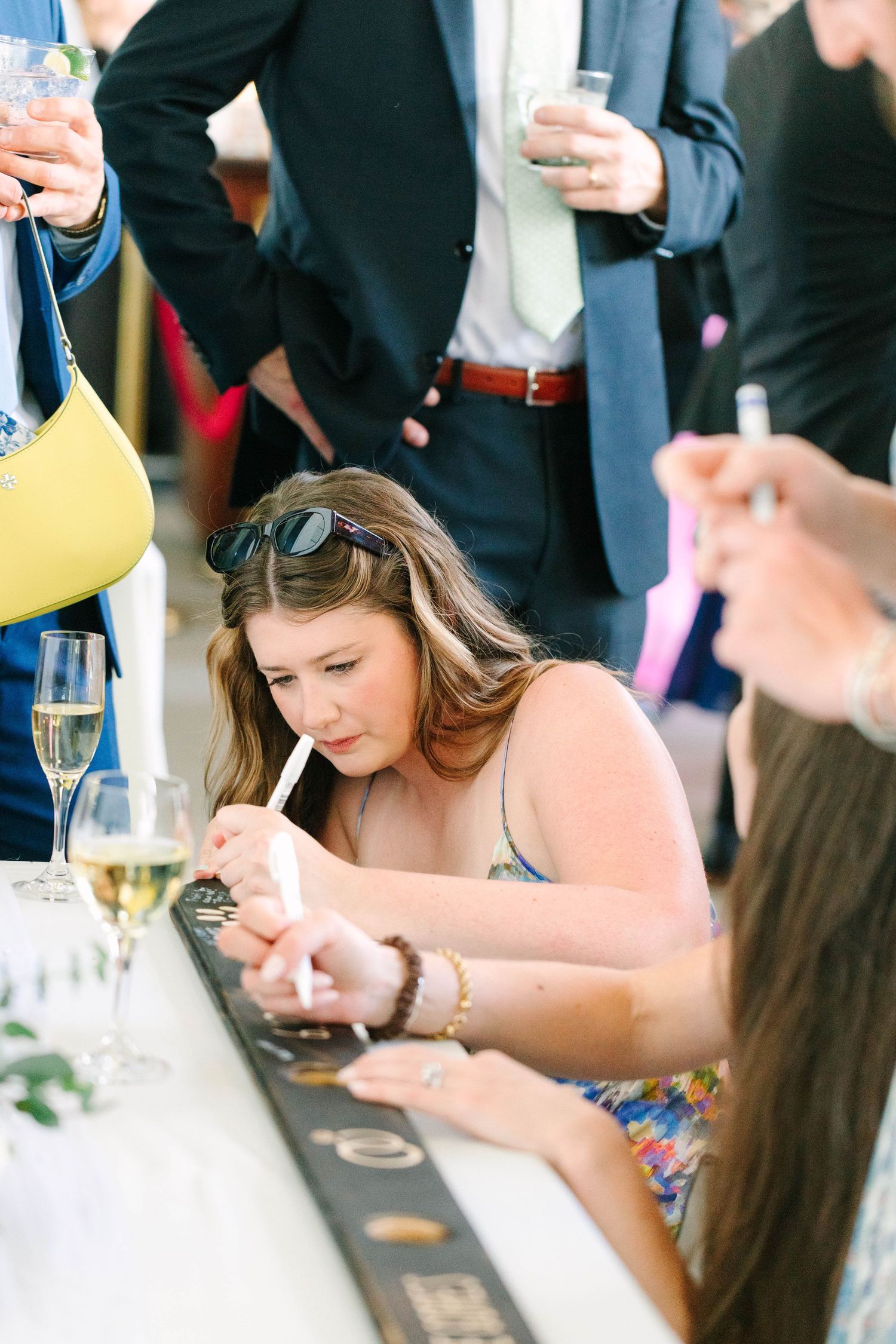Wedding guest signing seating chart at outdoor cocktail hour reception.