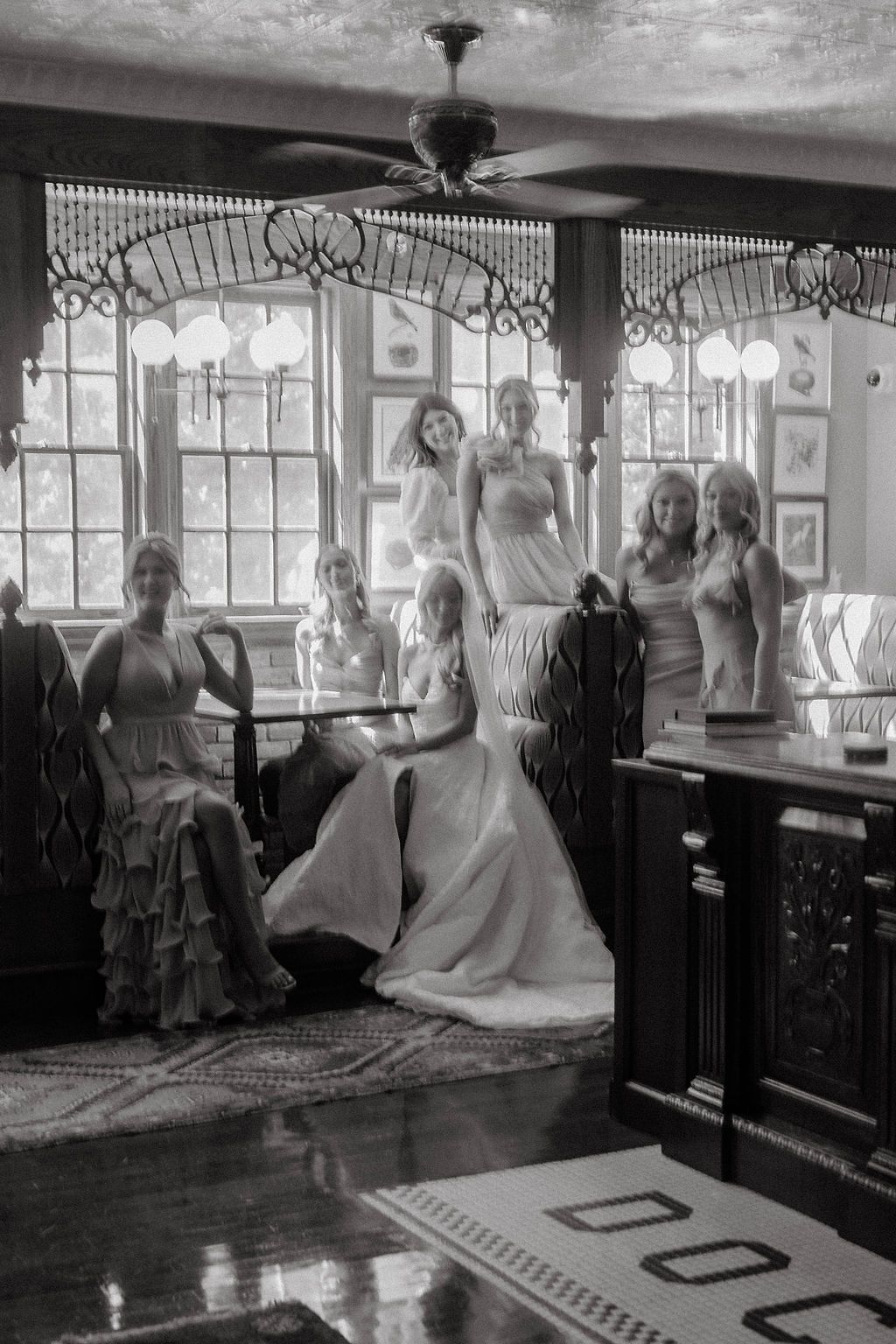 Black and white photo of bride and bridesmaids gathered in a charming vintage interior room.