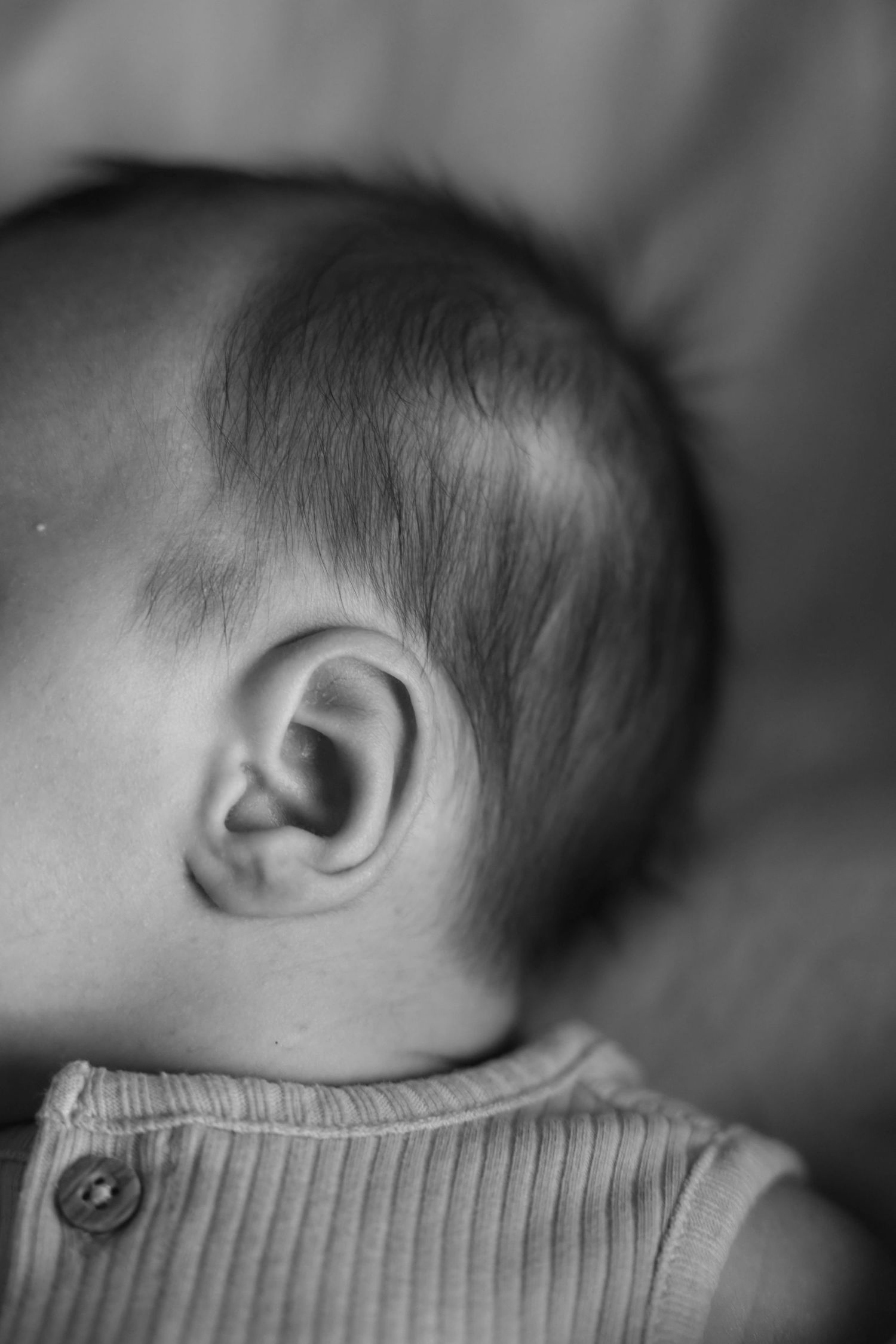 Black and white close-up portrait of a newborn babys ear and head profile.