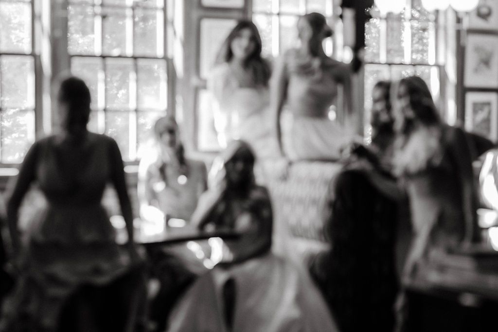 Artistic blurred black and white photo of bride and bridesmaids gathered in elegant venue.