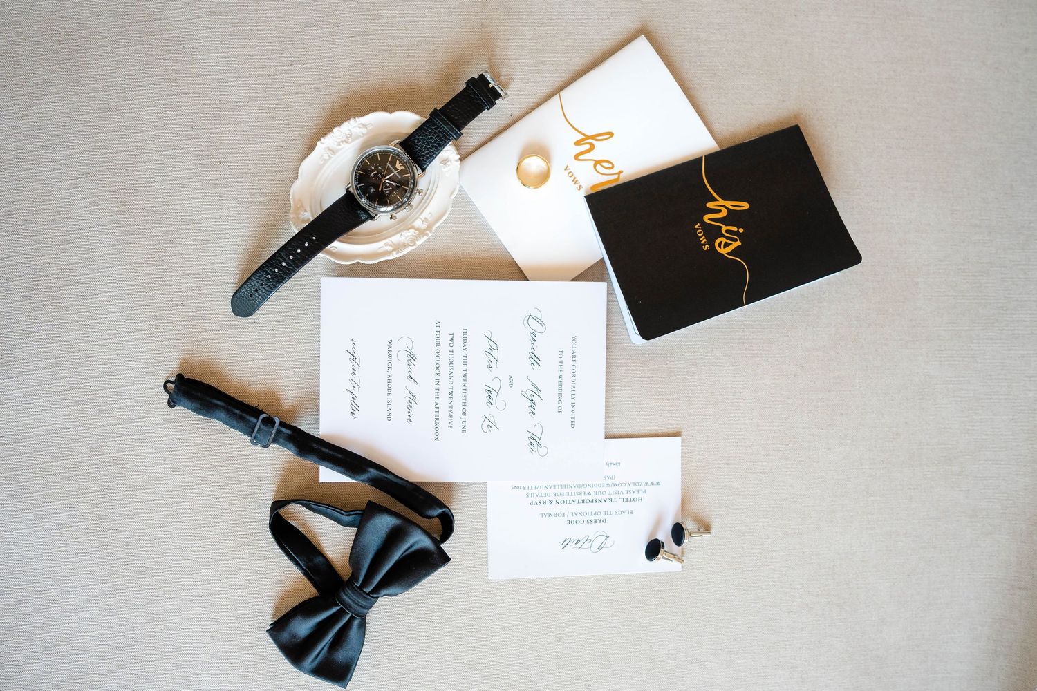 Classic black and white wedding flat lay with bow tie, watch, and invitation suite.