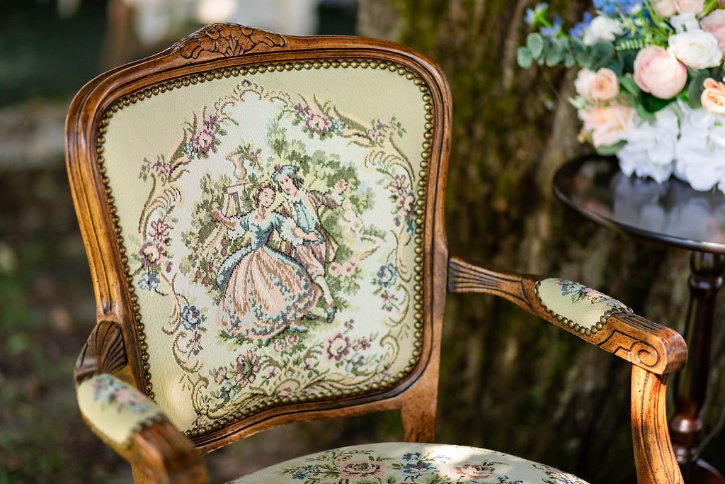 Vintage ornate wooden armchair with tapestry upholstery featuring a Victorian lady in a garden scene.