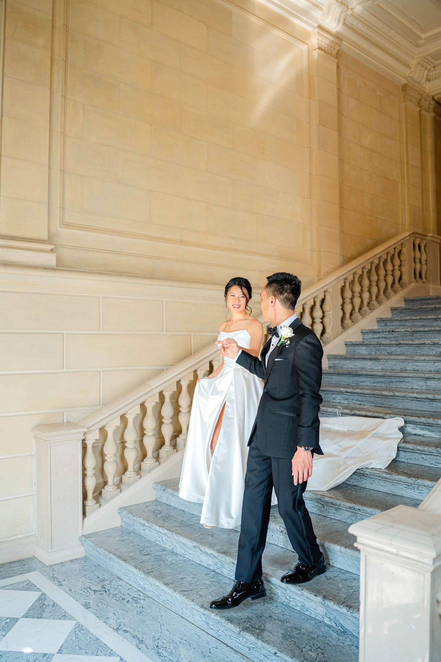 Bride and groom sharing romantic moment on elegant marble staircase with stone balustrade.