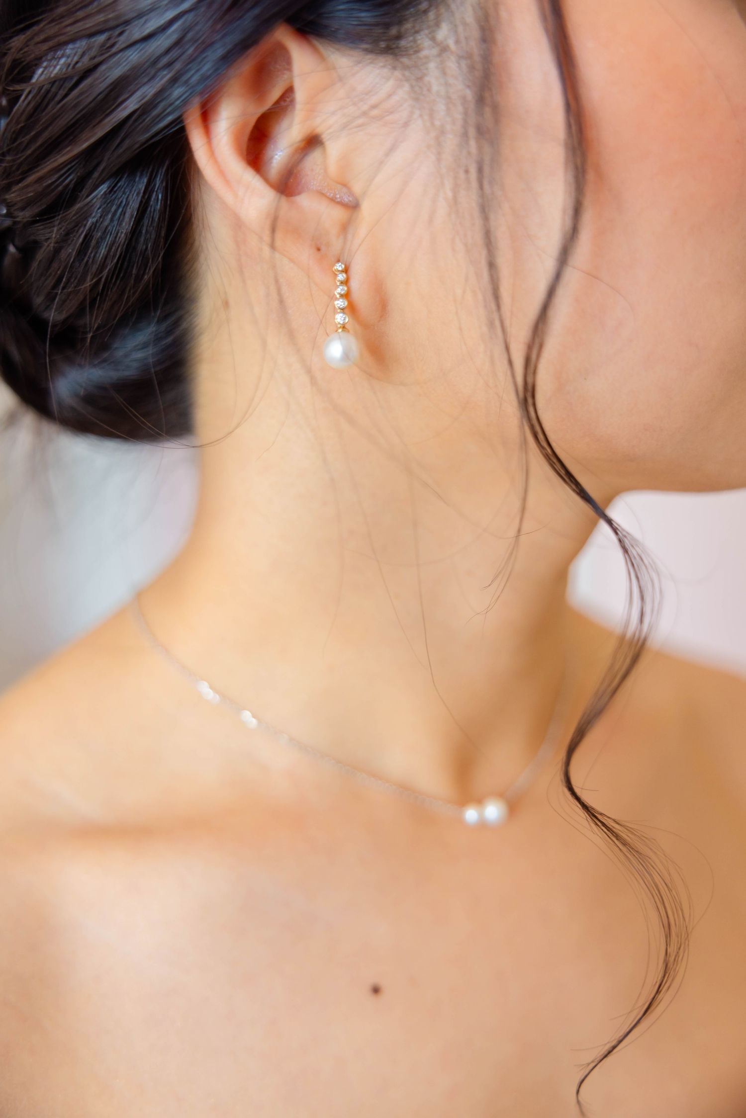 Close-up of a woman wearing pearl drop earrings and a delicate pearl necklace, perfect for bridal jewelry.