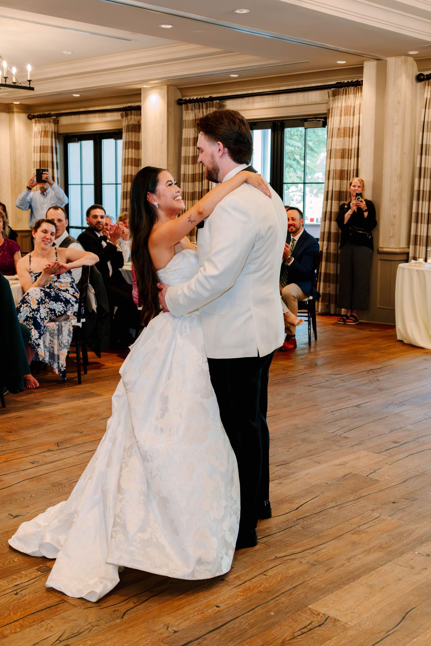 Newlyweds share intimate first dance while wedding guests watch and celebrate around them.