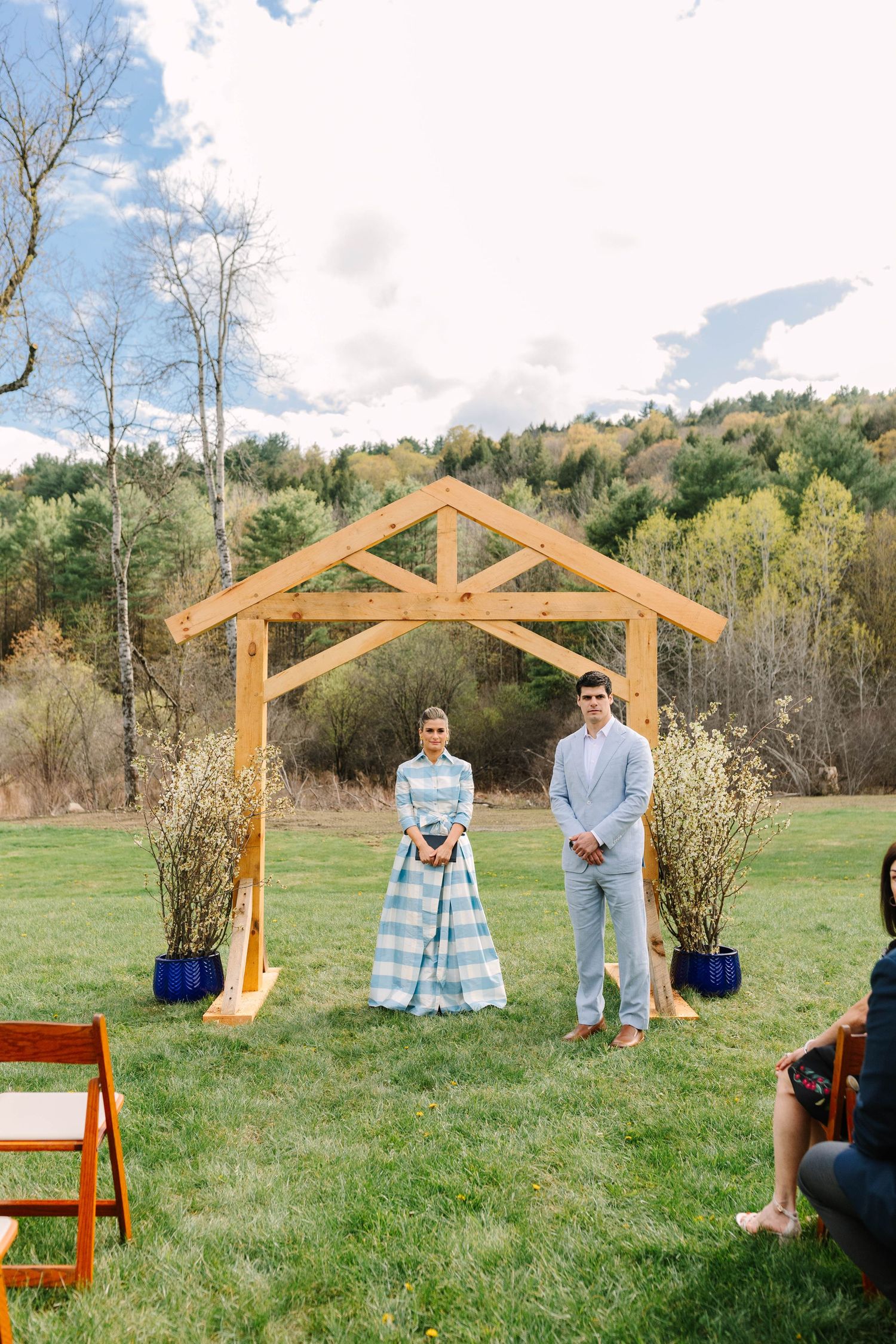 Bride and groom standing under a wooden arch during an outdoor wedding ceremony.