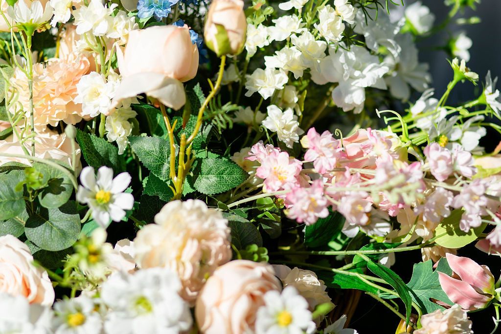 Soft pastel wedding floral arrangement featuring blush roses, white blooms, and greenery.