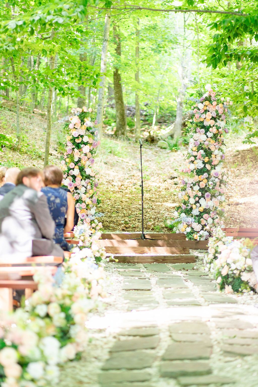 Floral wedding arch adorned with pink and white flowers at an outdoor woodland ceremony venue.