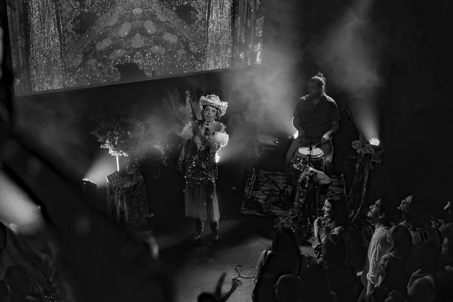 A concert performer on stage illuminated by dramatic spotlights in black and white.