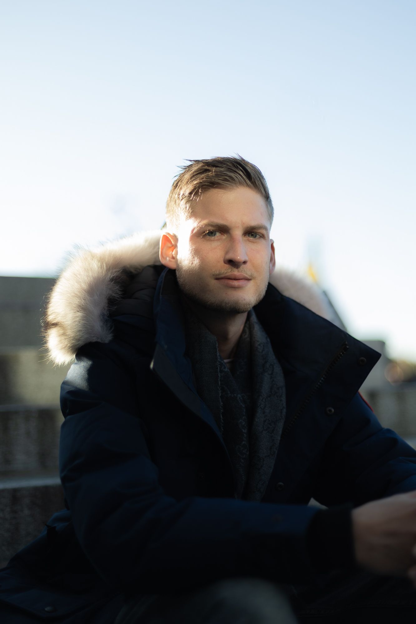 Person wearing navy winter coat with fur trim hood in natural lighting.