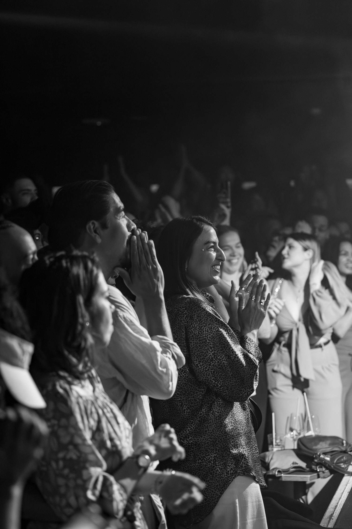 Concert attendees in the crowd cheer and applaud during a live performance.
