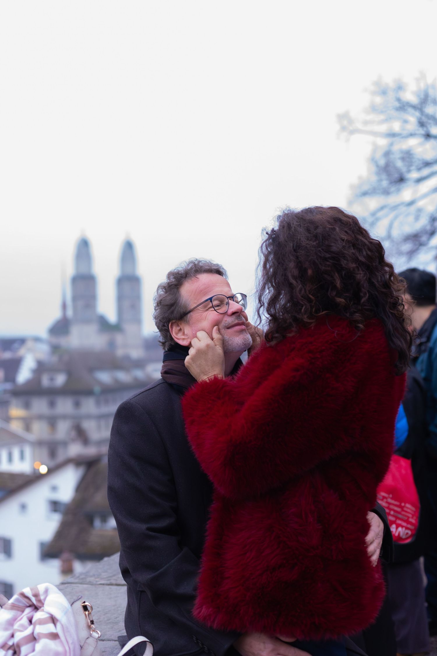 A romantic moment between two people with Zurich's twin spires visible in the background.