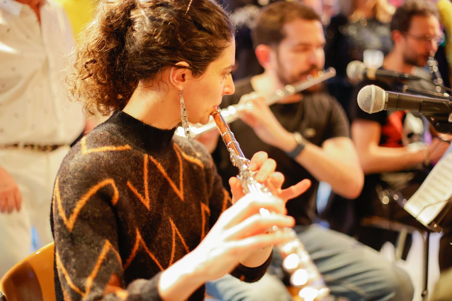 Musician performing at concert wearing zigzag pattern sweater with microphone setup.